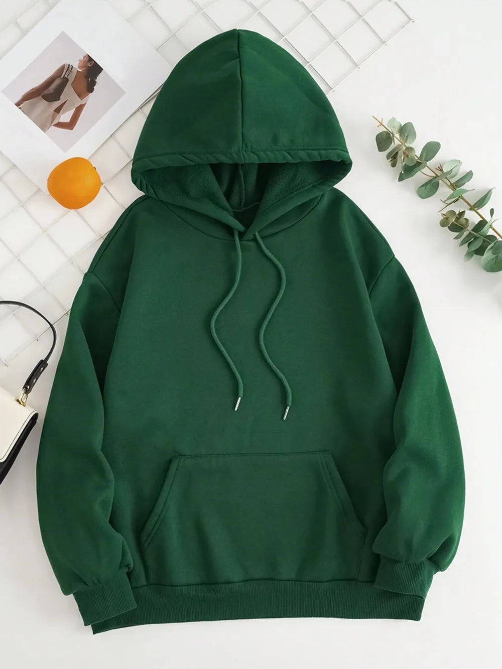 Green hoodie on a white background with decorative elements.