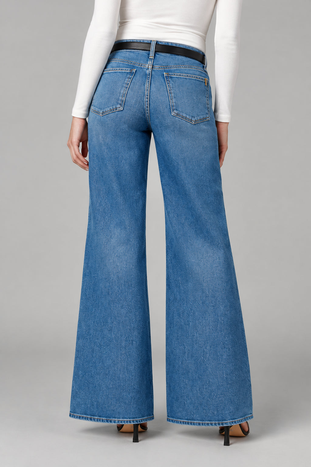 Person wearing blue wide-leg jeans on a plain background