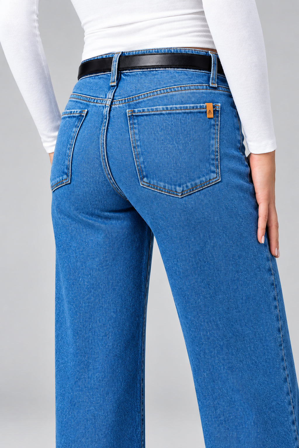 Person wearing blue jeans with a plain background