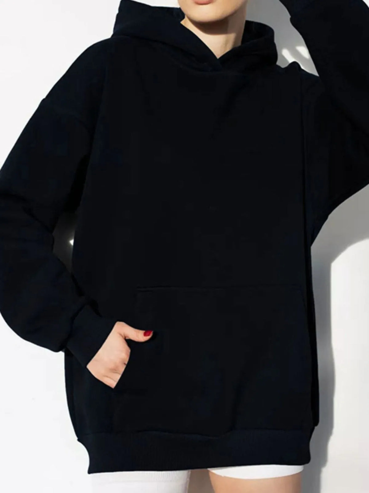 Person wearing a black hoodie and white pants against a white background