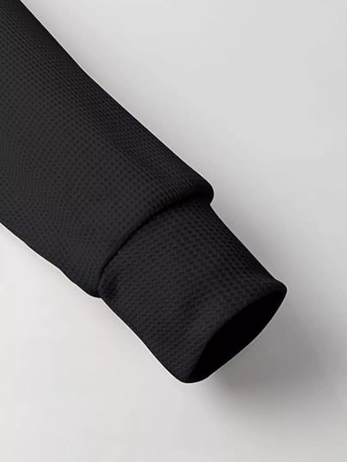 Black textured fabric roll on a light gray background
