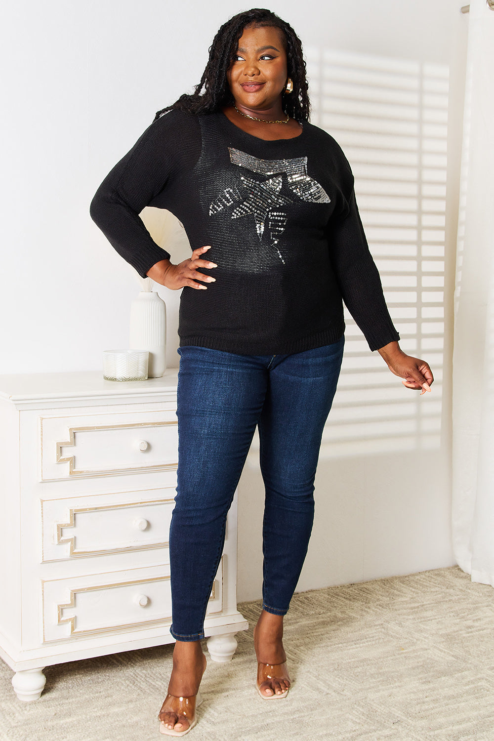 Woman wearing a black sequin top and blue jeans standing in a room with a white dresser.