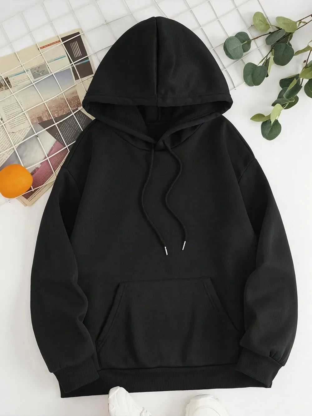 Black hoodie on a white surface with decorative elements