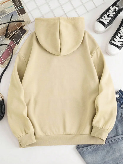Beige hoodie on a white surface with shoes and a basket in the background