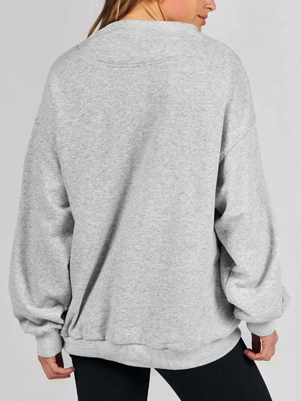 Person wearing a gray sweatshirt against a plain background
