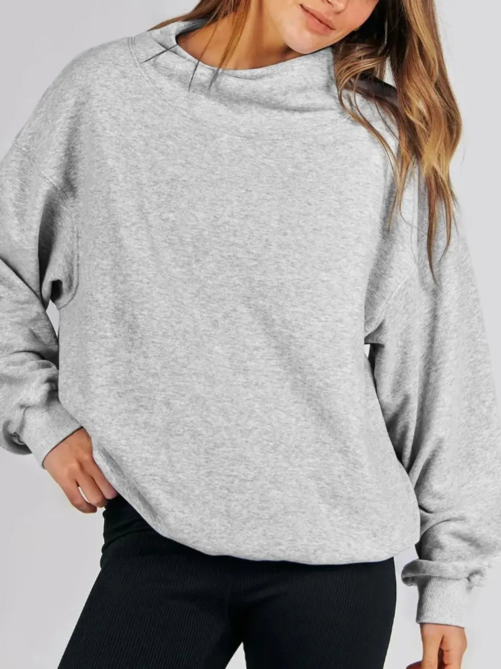 Person wearing a gray sweatshirt against a plain background
