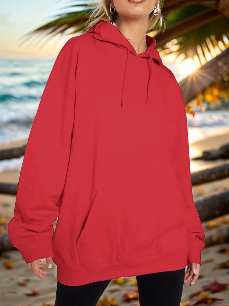 Person wearing a red hoodie on a beach with palm trees and ocean in the background