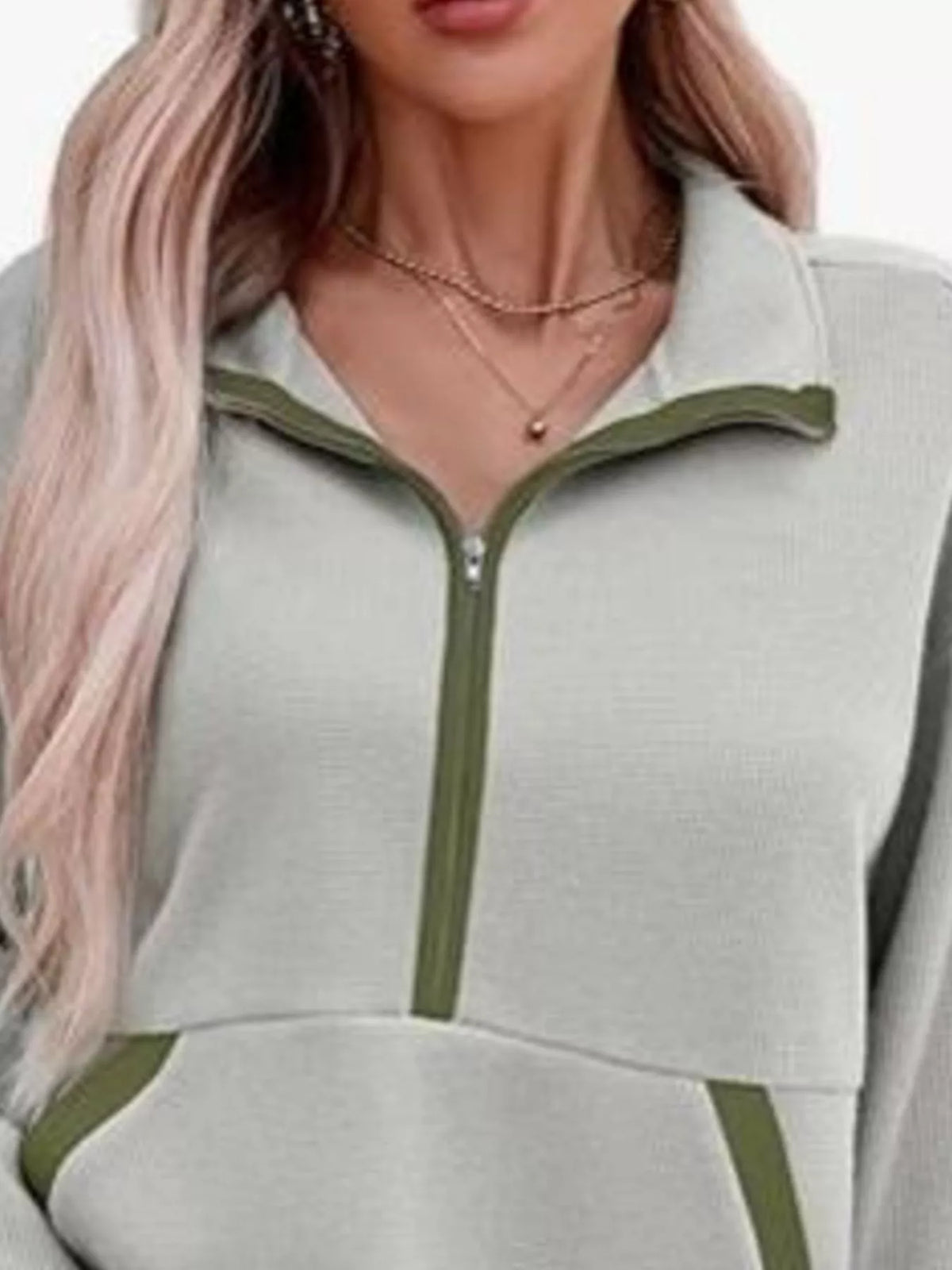 Close-up of a person wearing a light gray and green outfit with a zipper.