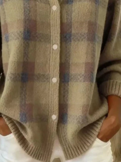 A close-up of a person wearing a fuzzy knit cardigan with a muted plaid pattern in beige, brown, and blue-gray, featuring white buttons and ribbed trim.
