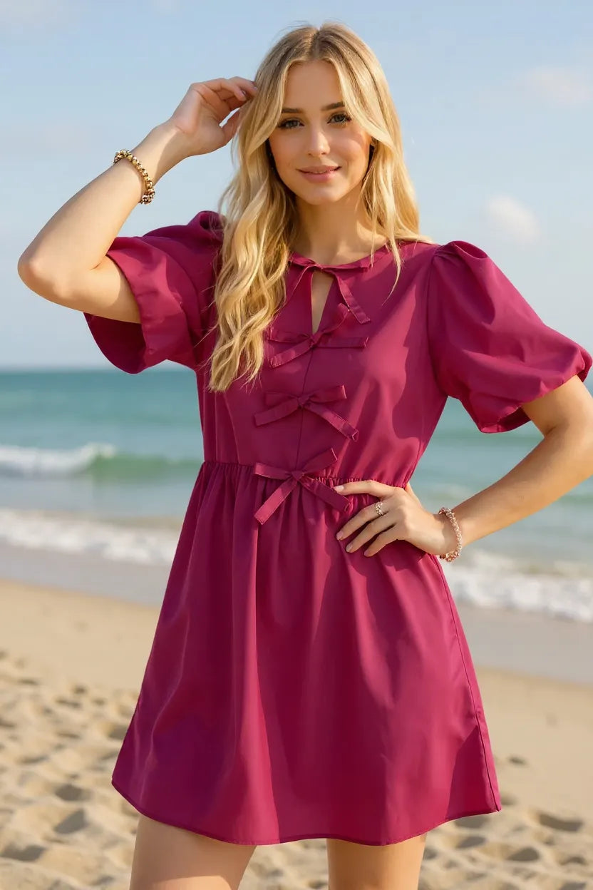 Woman in a pink dress standing on a beach with ocean view
