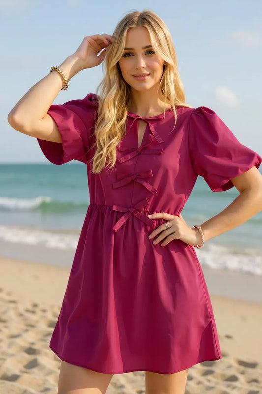 Woman in a pink dress standing on a beach with ocean view