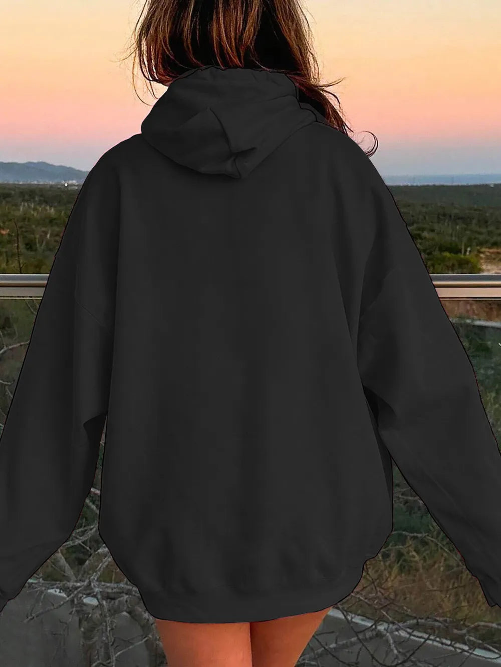 Person wearing a black hoodie with a scenic background
