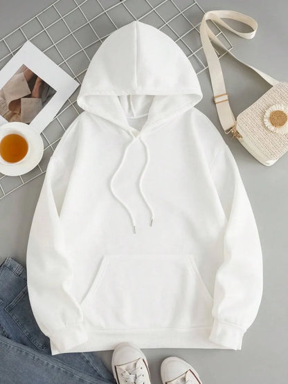 White hoodie on a gray surface with a bag and cup in the background