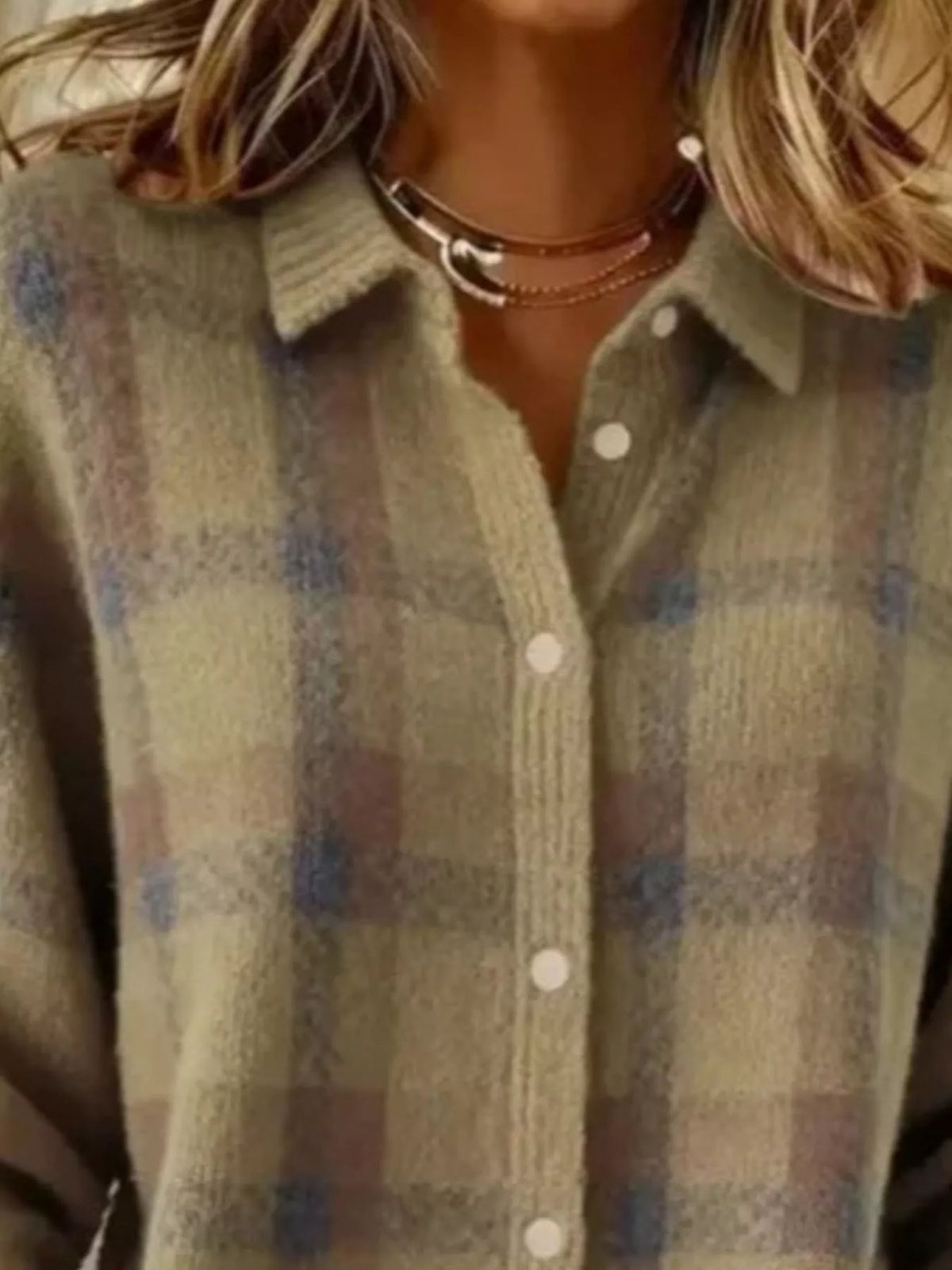 Close-up of a person wearing a fuzzy knit plaid button-up shirt in muted beige, olive green, and dusty blue tones, with layered necklaces visible.