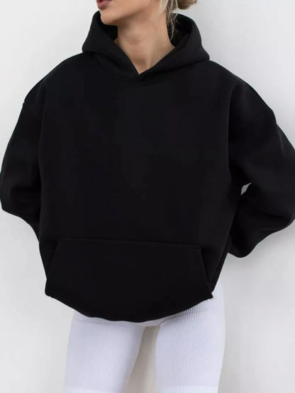 Person wearing a black hoodie and white pants against a white background
