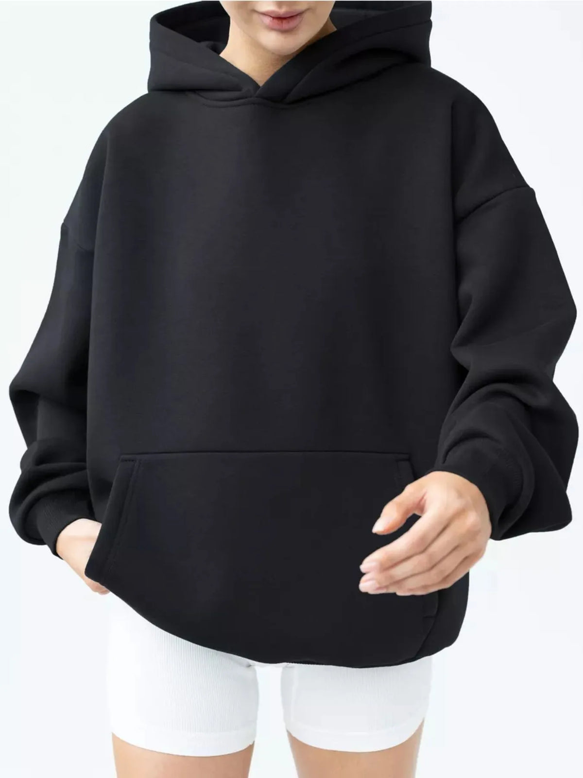 Person wearing a black hoodie and white pants against a white background