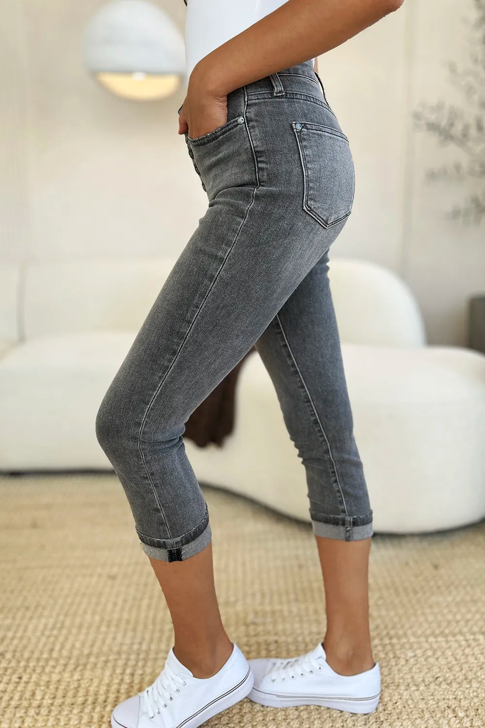 Person wearing gray jeans and white sneakers in a living room setting