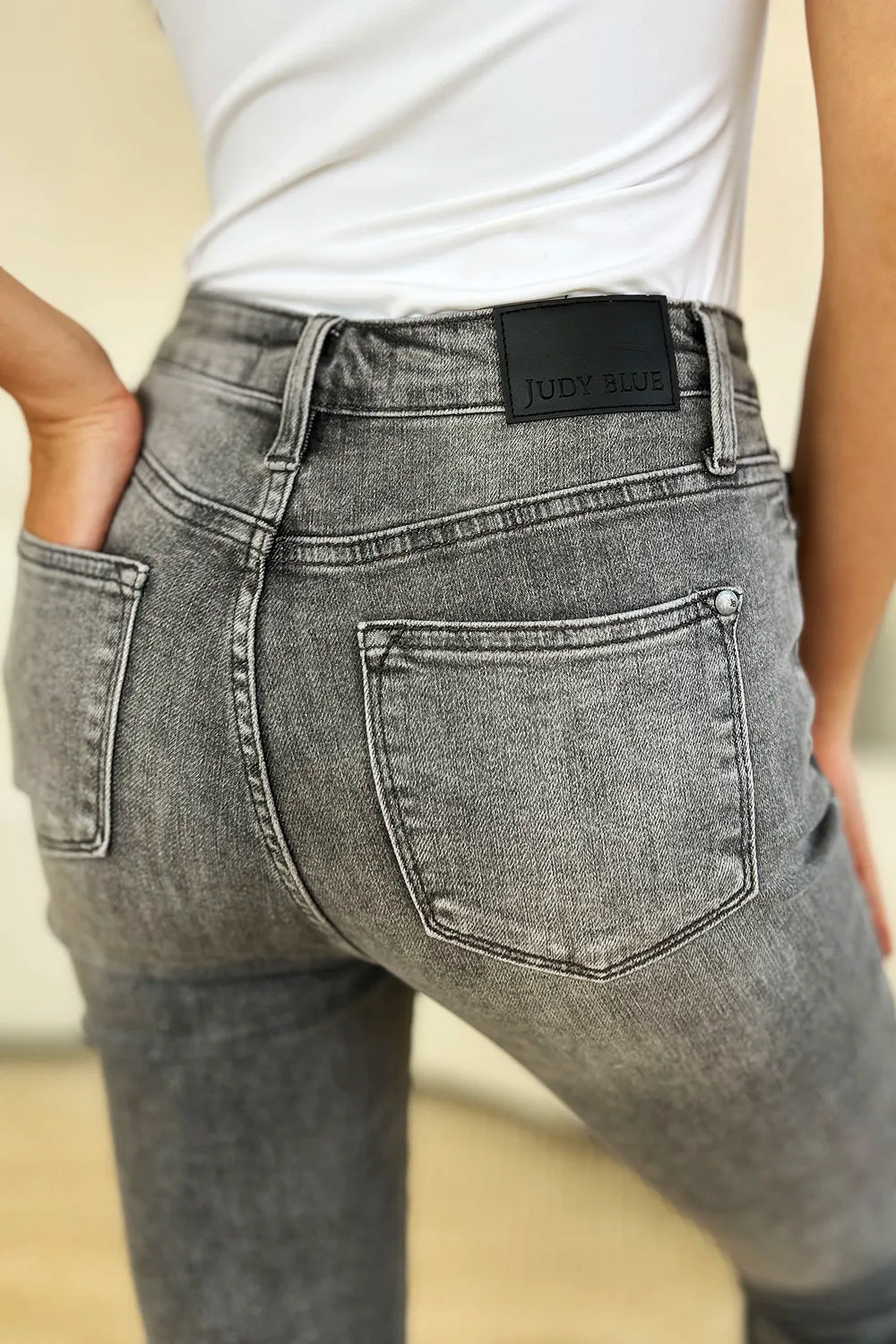 Person wearing gray jeans with a visible brand label on a neutral background