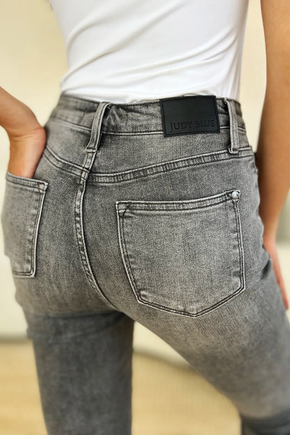 Person wearing gray jeans with a visible brand label on a neutral background