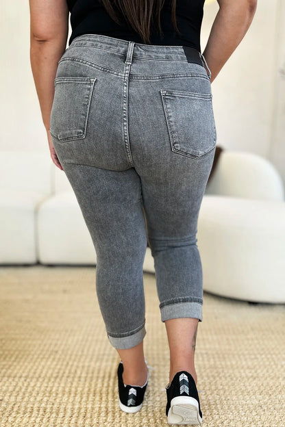 Person wearing gray jeans and black sneakers on a neutral background