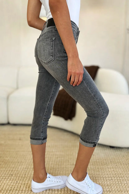 Person wearing gray jeans and white sneakers in a living room setting