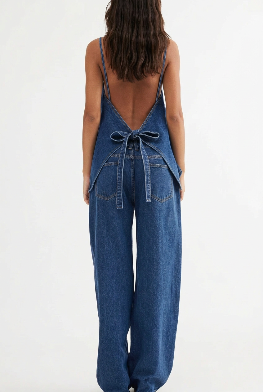 Lifestyle fashion photograph of a woman wearing a matching fisoew two piece indigo blue denim button down vest and wide leg trouser set outside a modern building for a Shopify boutique banner. Back view angles