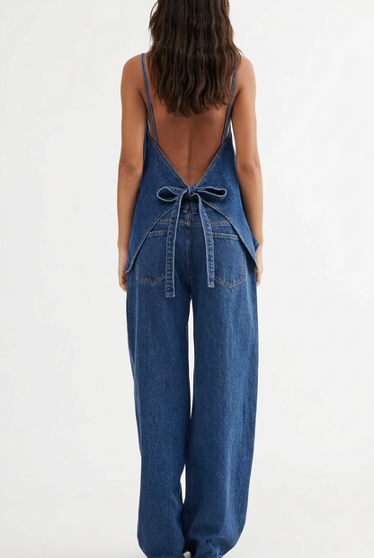 Lifestyle fashion photograph of a woman wearing a matching fisoew two piece indigo blue denim button down vest and wide leg trouser set outside a modern building for a Shopify boutique banner. Back view angles