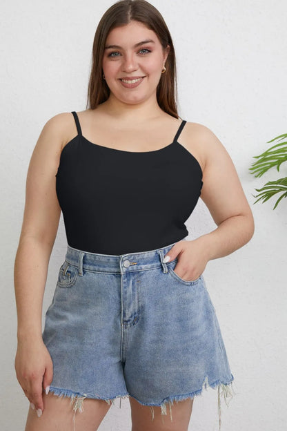 Woman wearing a black tank top and denim shorts against a white background