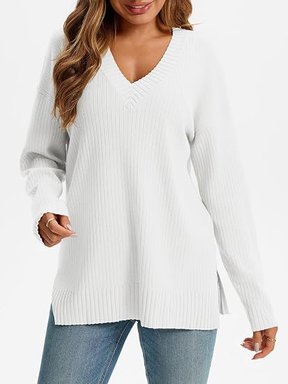 Woman wearing a white oversized ribbed knit V-neck sweater featuring long sleeves, side-slit hem, relaxed fit silhouette, and soft textured fabric for cozy everyday styling.