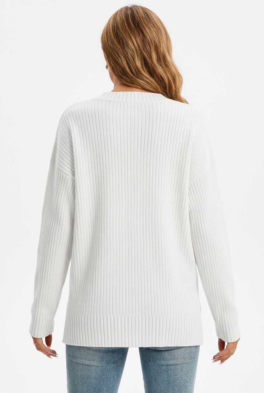 Woman wearing a white oversized ribbed knit V-neck sweater featuring long sleeves, side-slit hem, relaxed fit silhouette, and soft textured fabric for cozy everyday styling. Color & Features and Specs