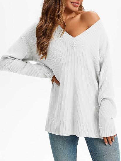 Woman wearing a white oversized ribbed knit V-neck sweater featuring long sleeves, side-slit hem, relaxed fit silhouette, and soft textured fabric for cozy everyday styling.