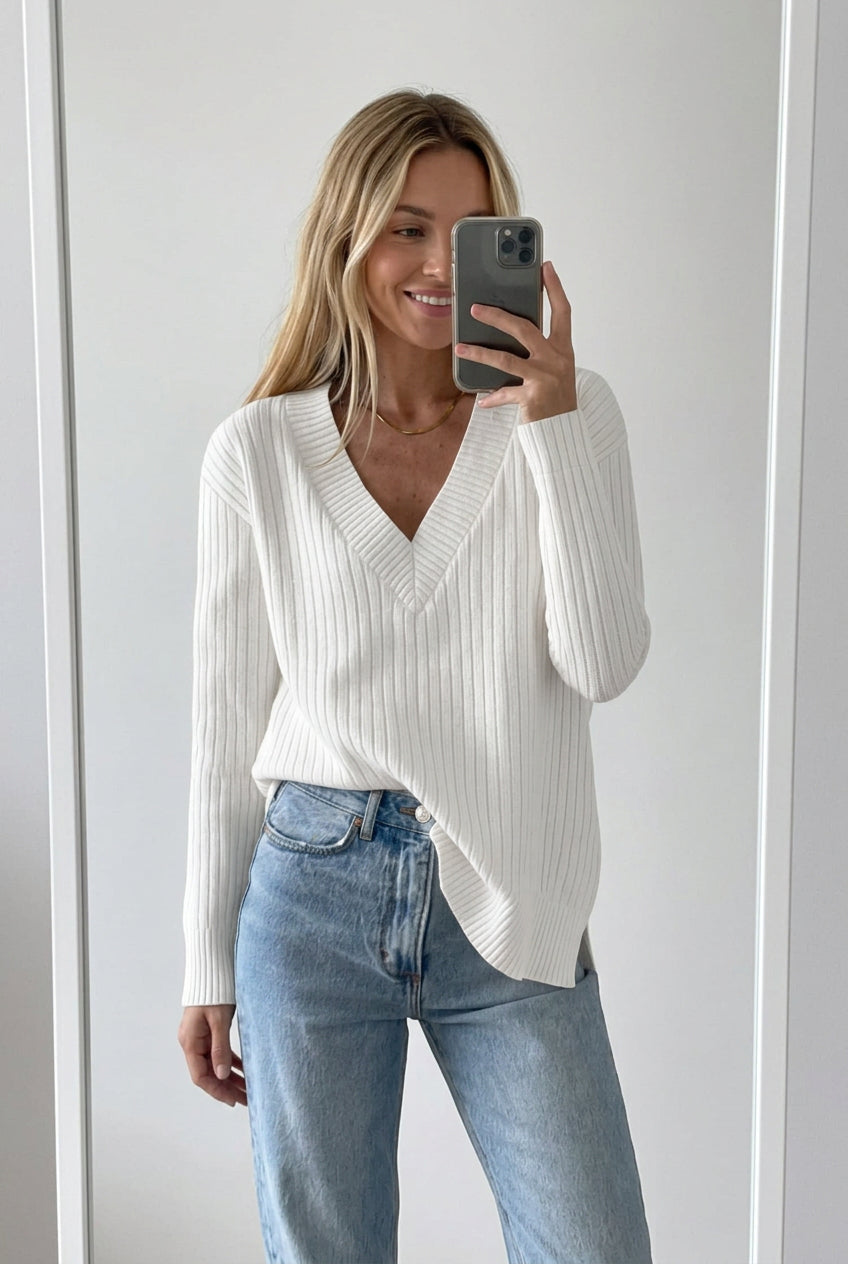 White ribbed sweater worn by a person with light blue jeans on a white background