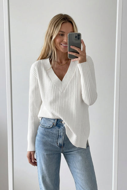White ribbed sweater worn by a person with light blue jeans on a white background