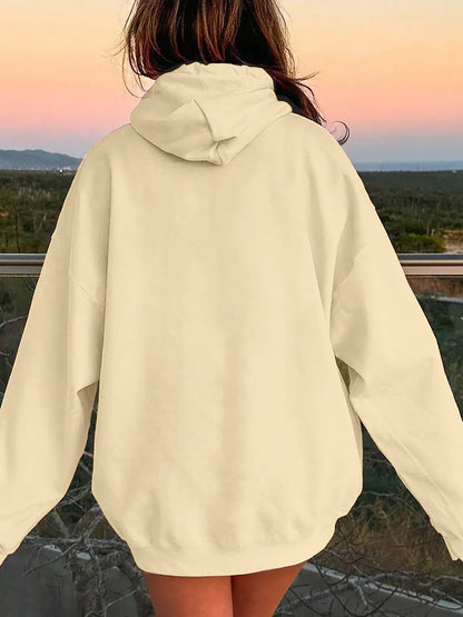 Person wearing a beige hoodie with a scenic background