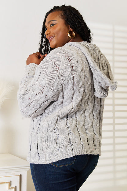 Woman wearing a gray cable knit cardigan in a home setting