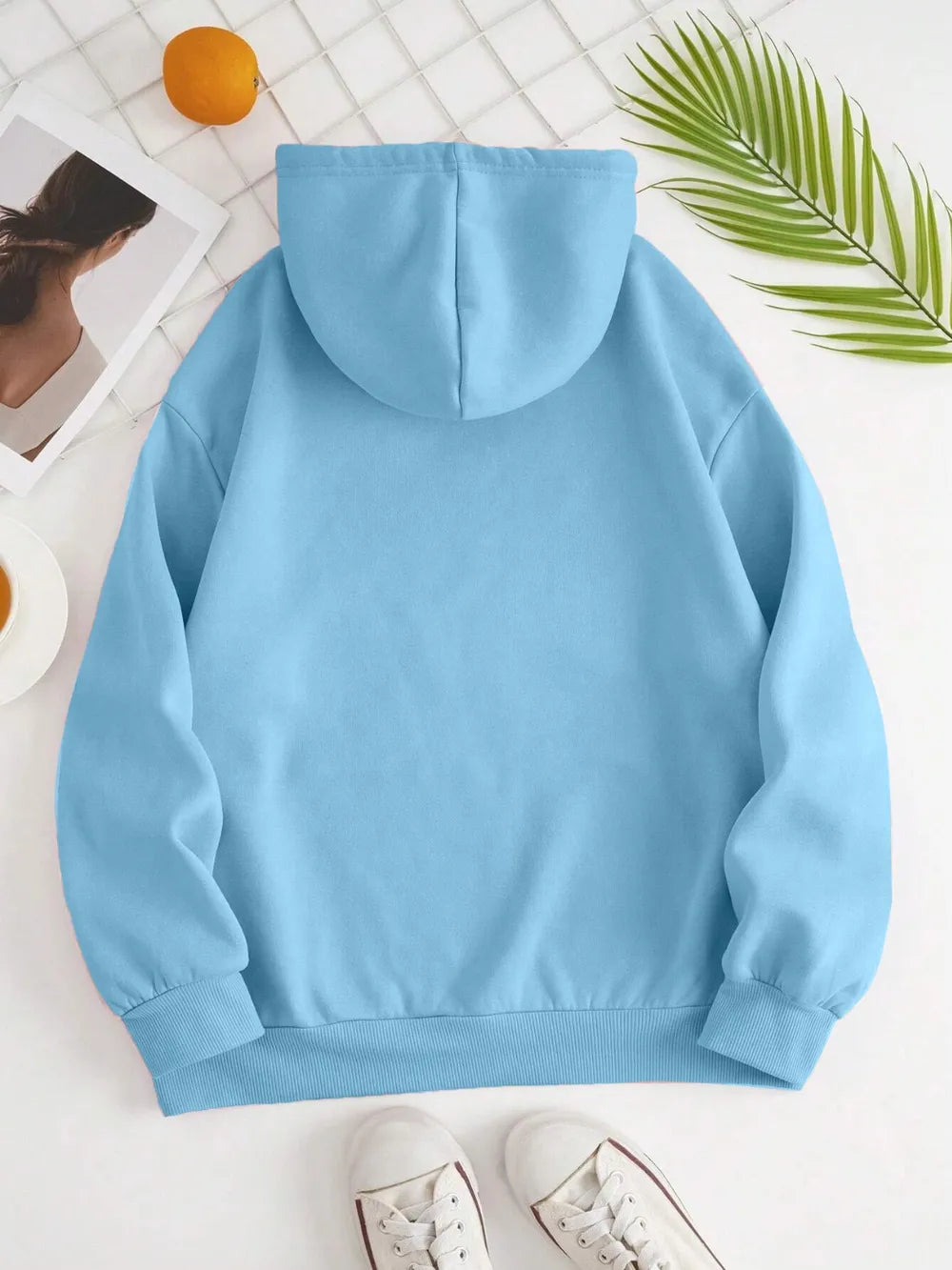 Light blue hoodie on a white surface with a blurred background
